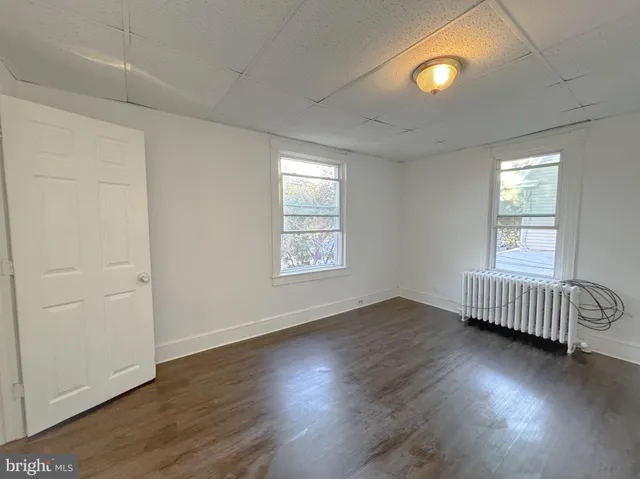 a view of an empty room with wooden floor and windows