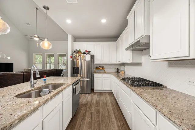 a kitchen with granite countertop a sink a counter space appliances and cabinets