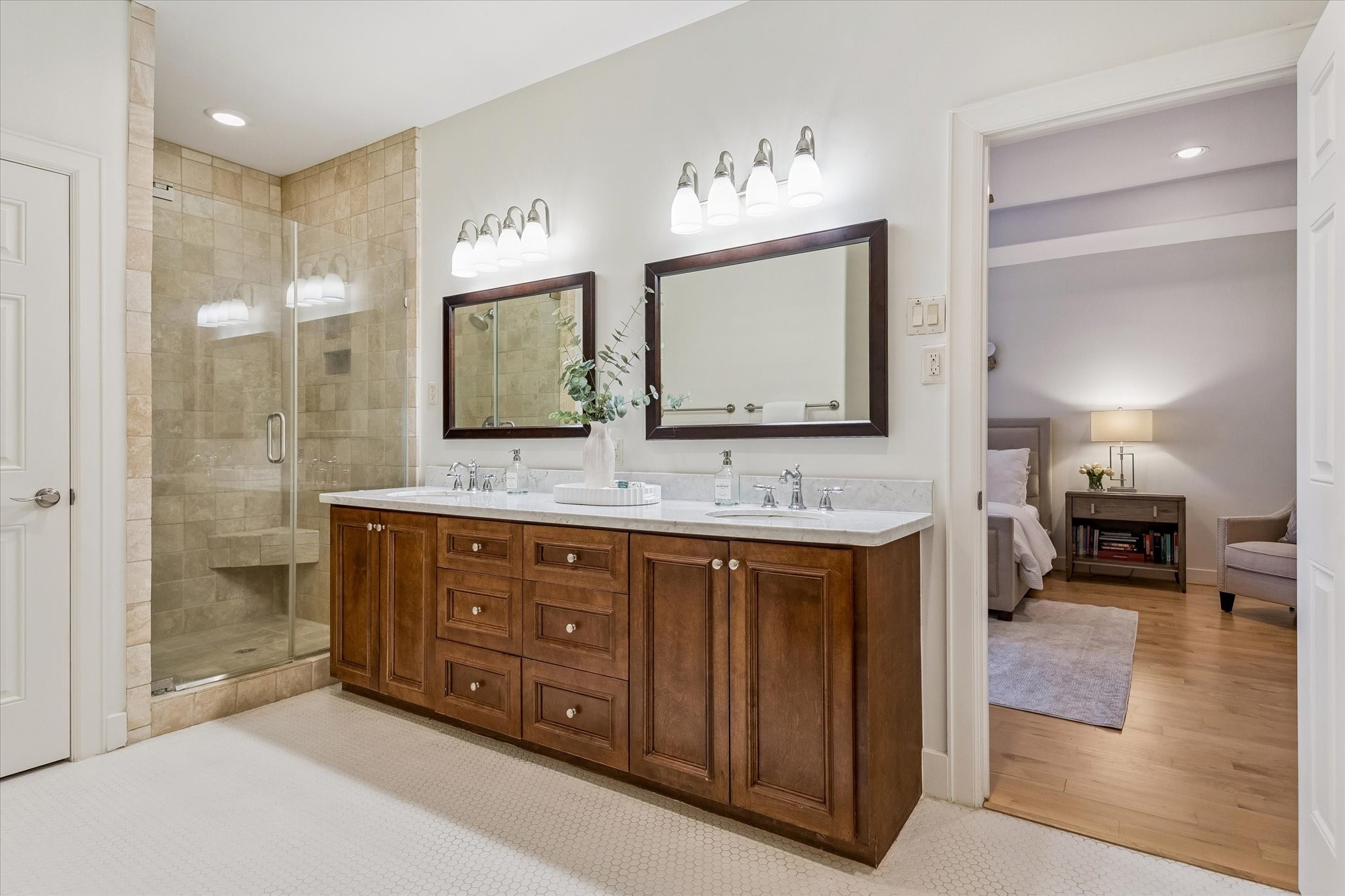 4010 Milton Street Houston, TX 77005 - Photo 22 of 49 PRIMARY BATHROOM. The warm toned cabinetry, a feature of the home, continues into the primary bathroom. Together with marble countertops and white tiled flooring the primary bathroom feels modern and fresh. It connects to a really large walk-in closet (and also access to the fifth bedroom/game room but that would be really easy to close off).