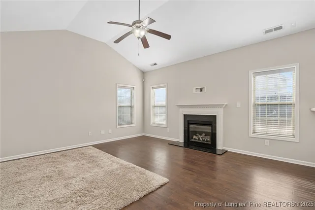 an empty room with windows fireplace and wooden floor