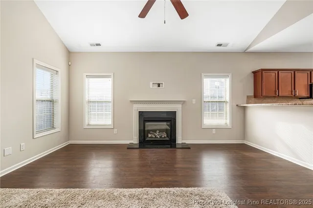 an empty room with windows and fireplace