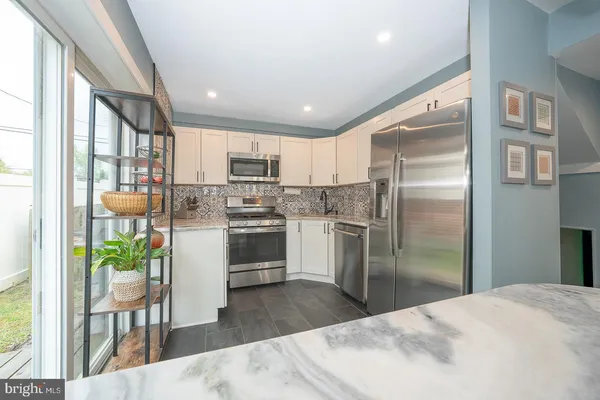 a kitchen with stainless steel appliances a refrigerator a oven a sink a stove and white cabinets