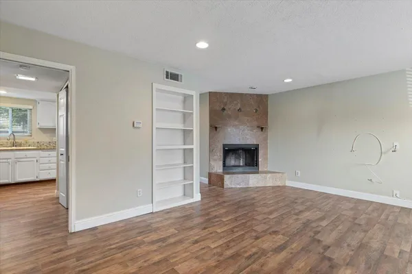 a view of empty room with wooden floor and fireplace