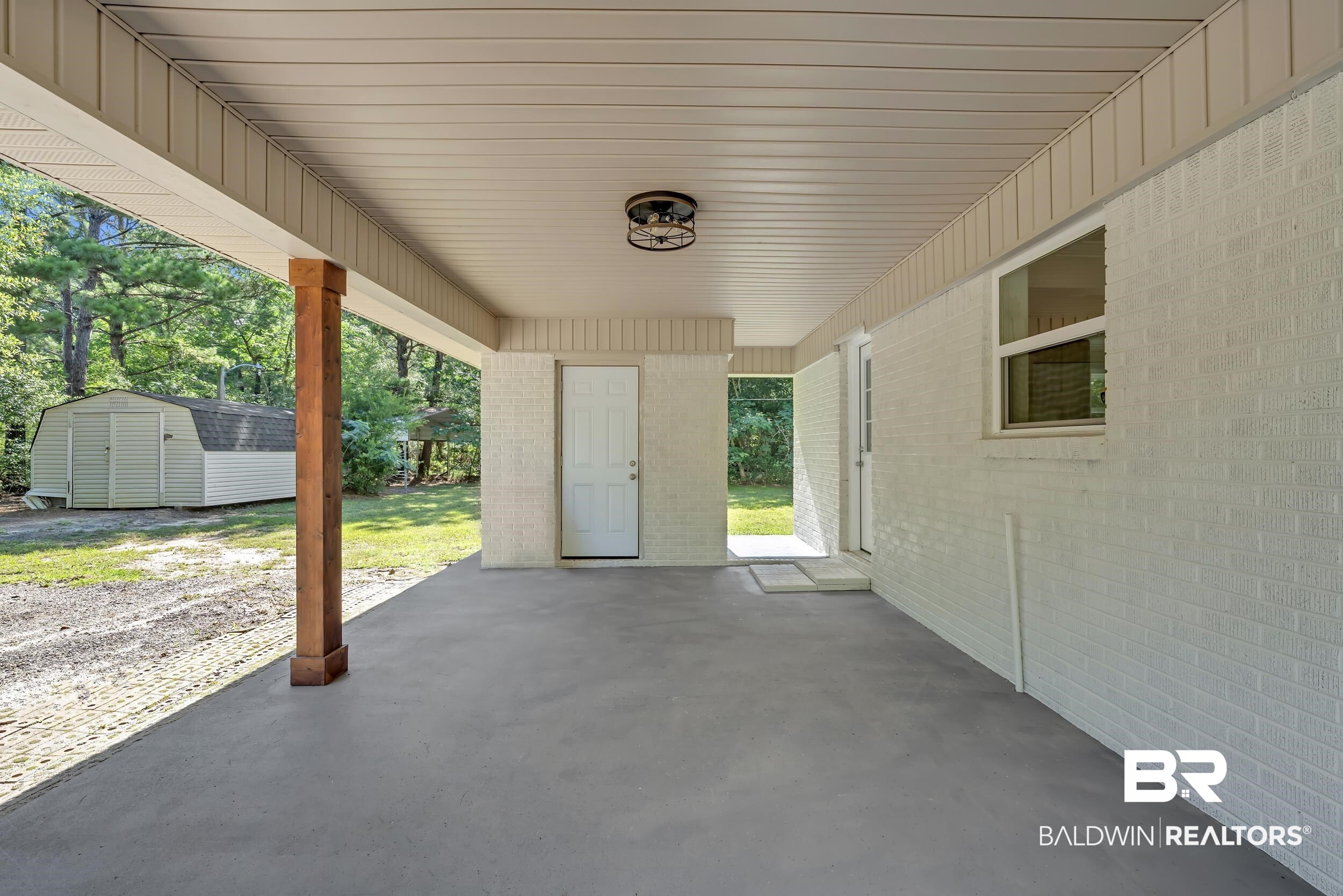 2712 Shelton Beach Rd Extension Mobile, AL 36613 - Photo 4 of 24 Covered patio featuring a concrete floor, painted brick wall, and a wood-finish support column