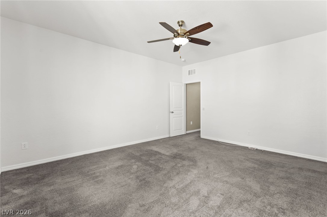 11048 Prairie Grove Road Las Vegas, NV 89179 - Photo 47 of 75 A spacious bedroom featuring plush gray carpeting and an overhead ceiling fan for optimal comfort.