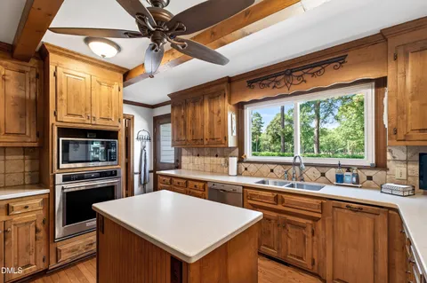 a kitchen with stainless steel appliances a sink a stove a refrigerator cabinets and a large window