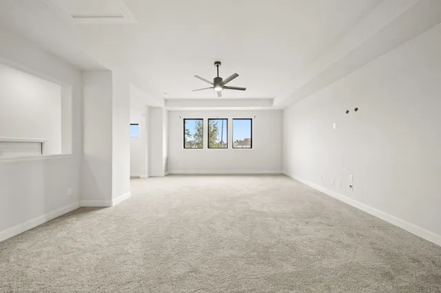 an empty room with a window and a ceiling fan