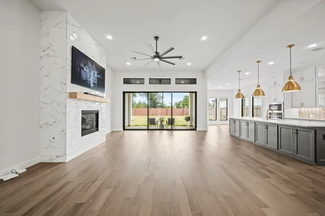 a view of an empty room with wooden floor and a fireplace
