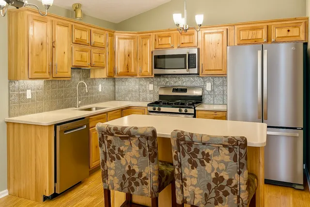 a large kitchen with stainless steel appliances granite countertop a granite counter tops and a view of living room