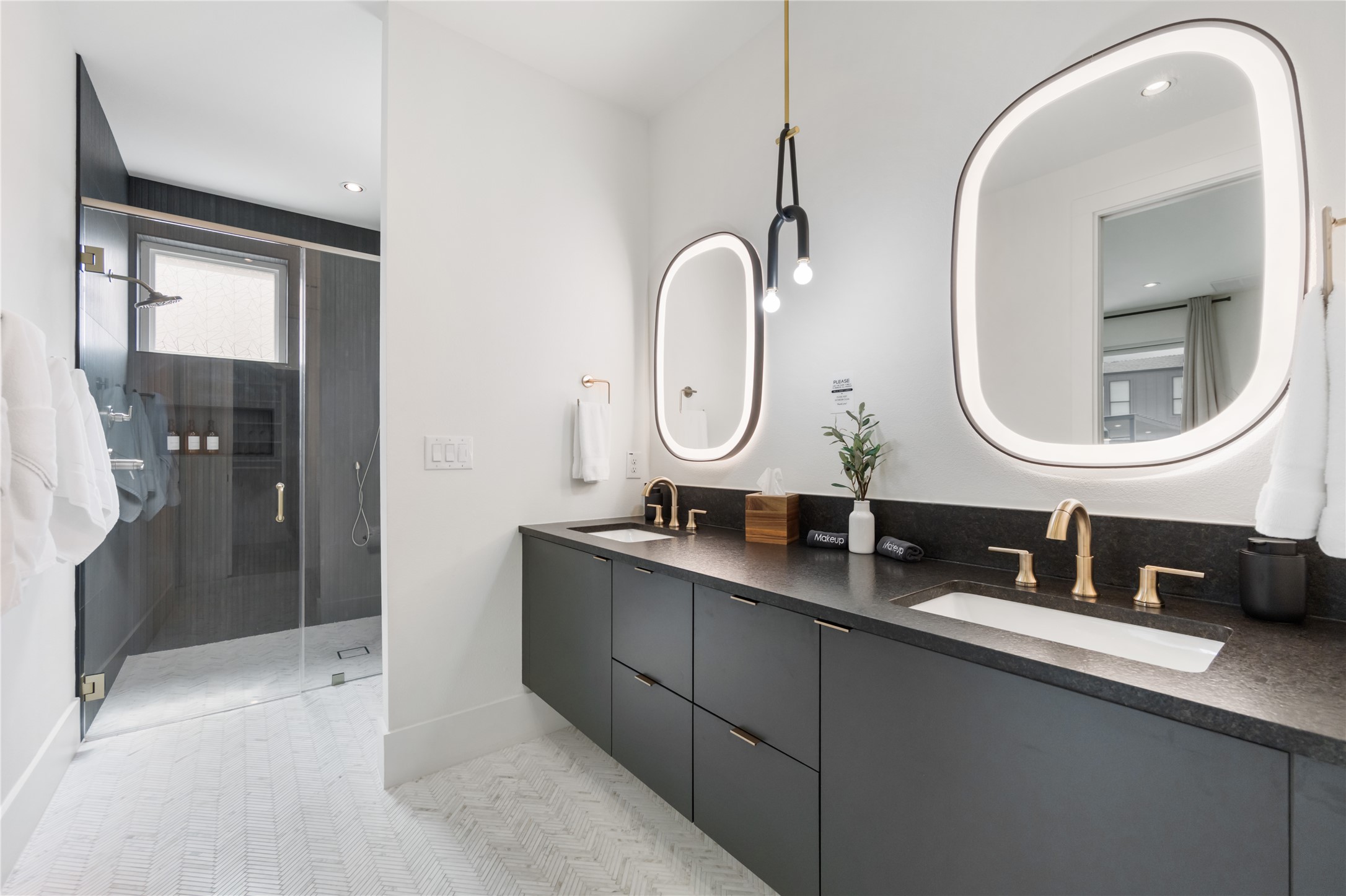 3201 Holton Street Austin, TX 78702 - Photo 18 of 39 A floating double vanity with crisp black countertops pairs seamlessly with backlit statement mirrors and a spacious walk-in shower for a high-end, spa-like experience.