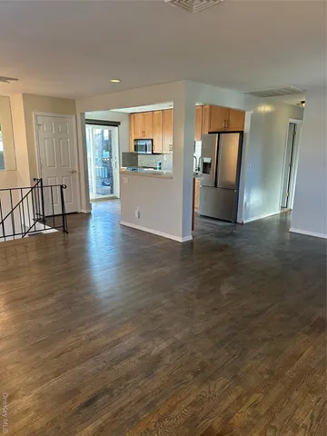 a view of an empty room with wooden floor and window