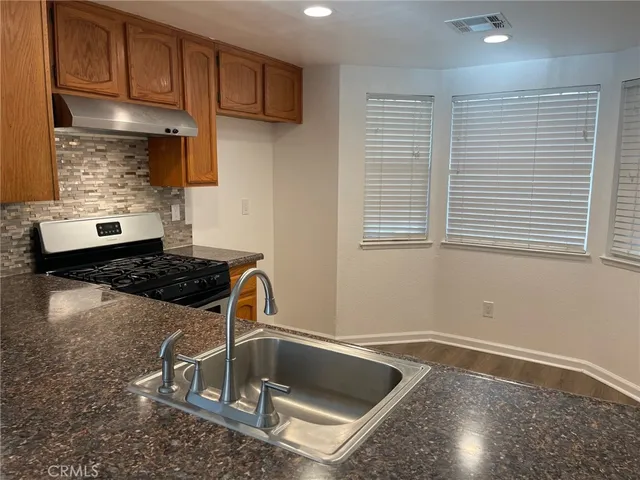 a kitchen with kitchen island granite countertop a sink stove and cabinets