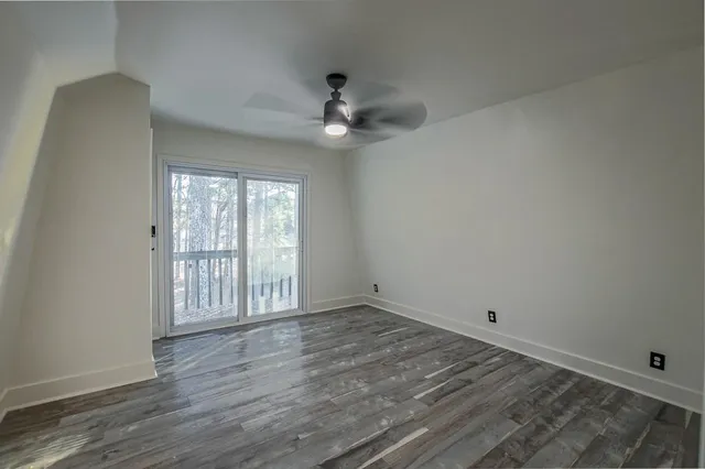 an empty room with wooden floor fan and windows