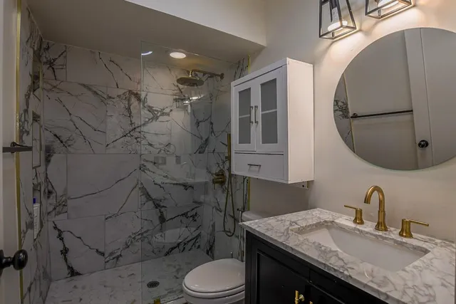 a bathroom with a granite countertop toilet sink and mirror