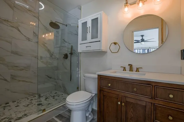a bathroom with a toilet a sink a mirror and shower