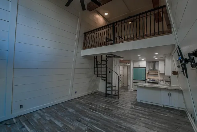 a view of a hallway with wooden floor and a kitchen