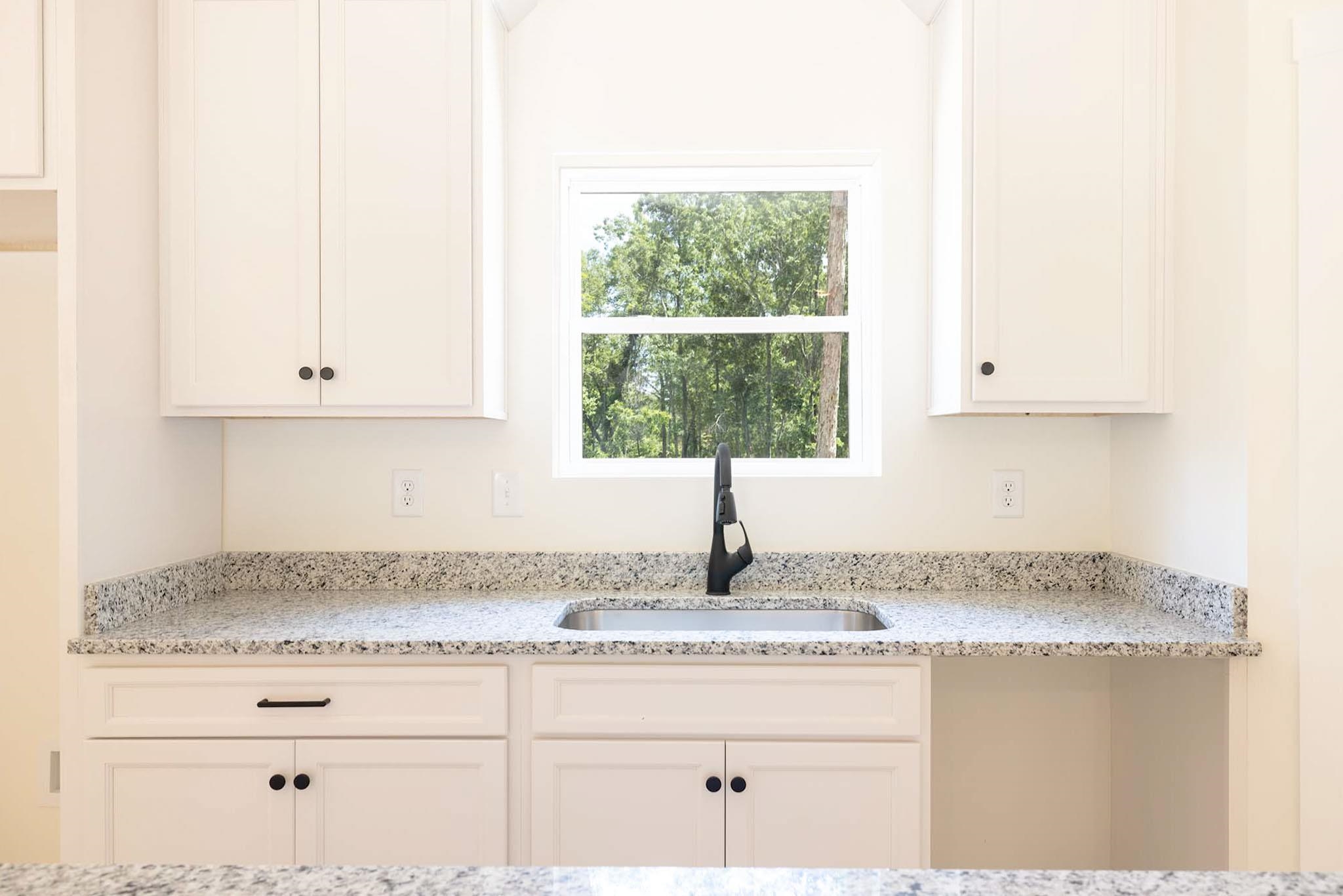 37 William Teague Lane Ramer, TN 38367 - Photo 21 of 39 White shaker cabinetry with dark hardware, speckled countertops, stainless steel undermount sink, and a black gooseneck faucet