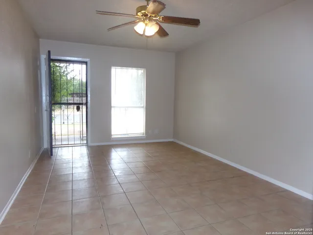 an empty room with chandelier fan and windows