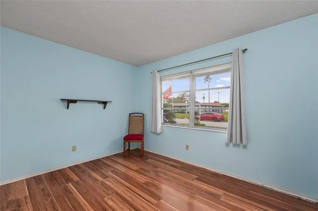 a view of an empty room with window and wooden floor
