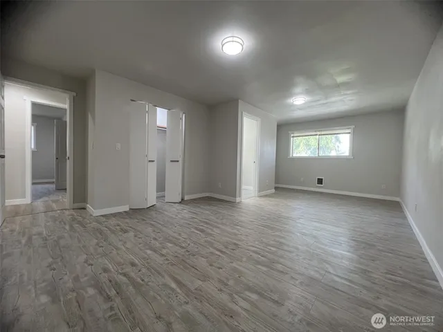 an empty room with wooden floor and windows