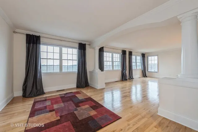 a view of an empty room with window and wooden floor