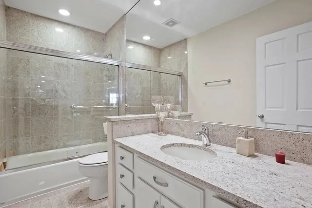 a bathroom with a granite countertop sink a toilet and shower