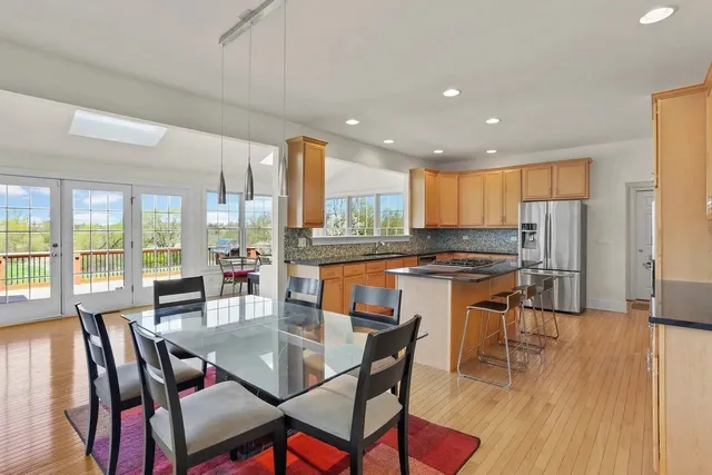 a kitchen with stainless steel appliances granite countertop a table chairs and a refrigerator