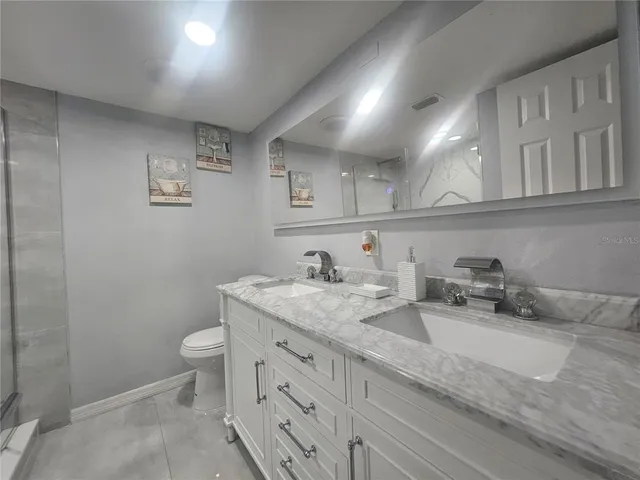 a bathroom with a granite countertop sink and a toilet