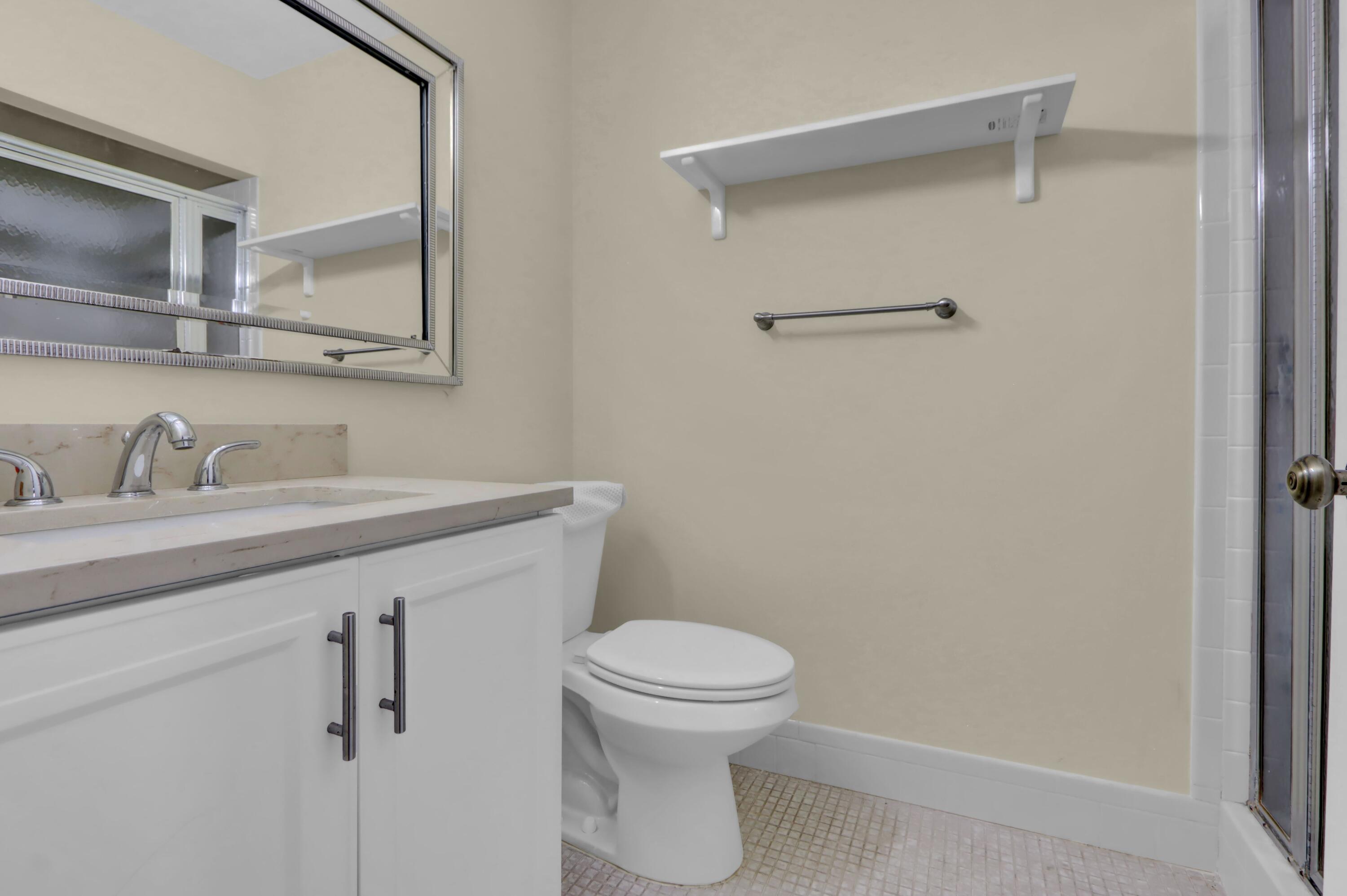 14050 Nesting Way, Unit B Delray Beach, FL 33484 - Photo 11 of 18 a bathroom with a sink a toilet and a mirror