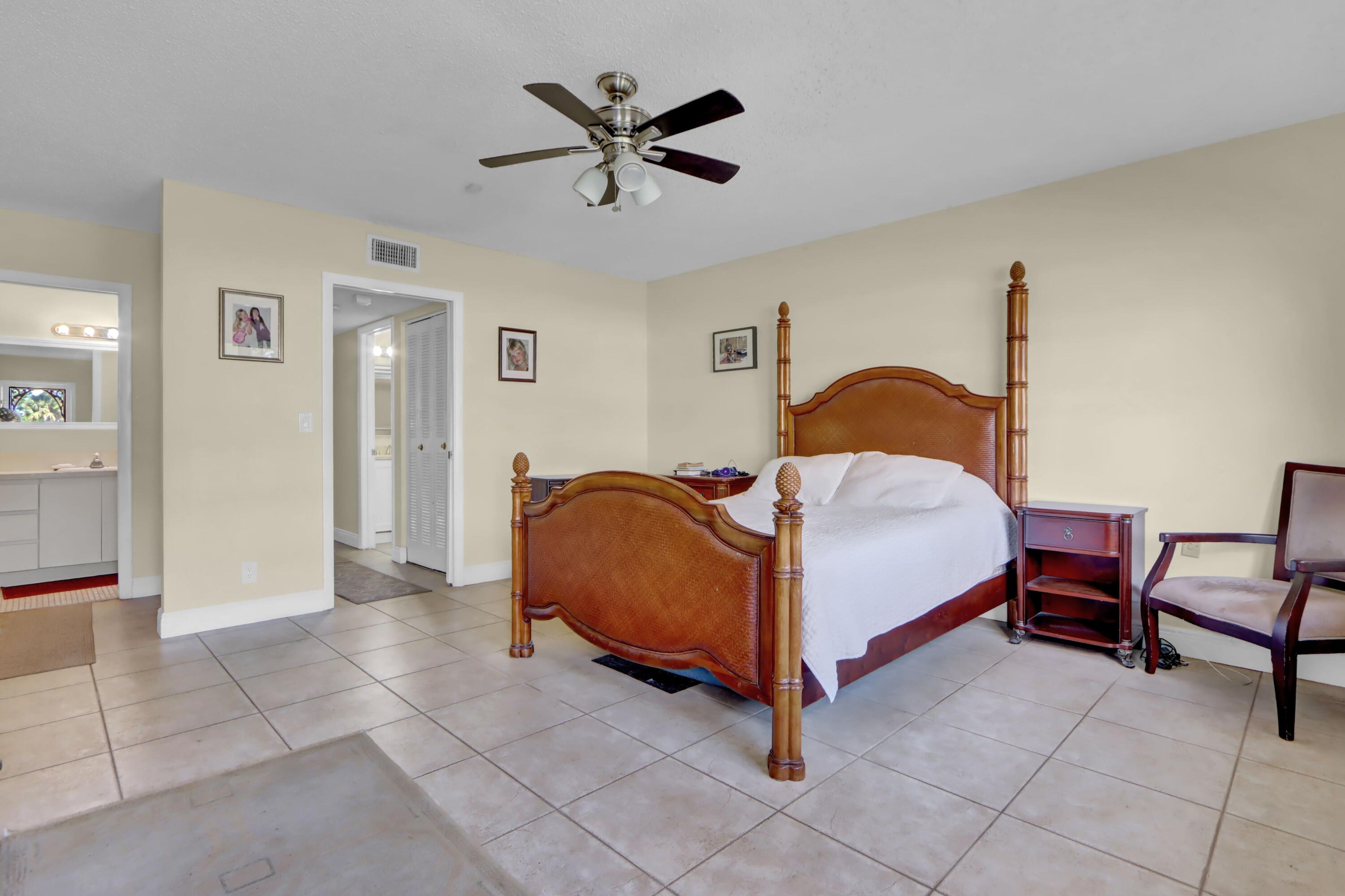 14050 Nesting Way, Unit B Delray Beach, FL 33484 - Photo 13 of 18 a bedroom with a bed and a chandelier
