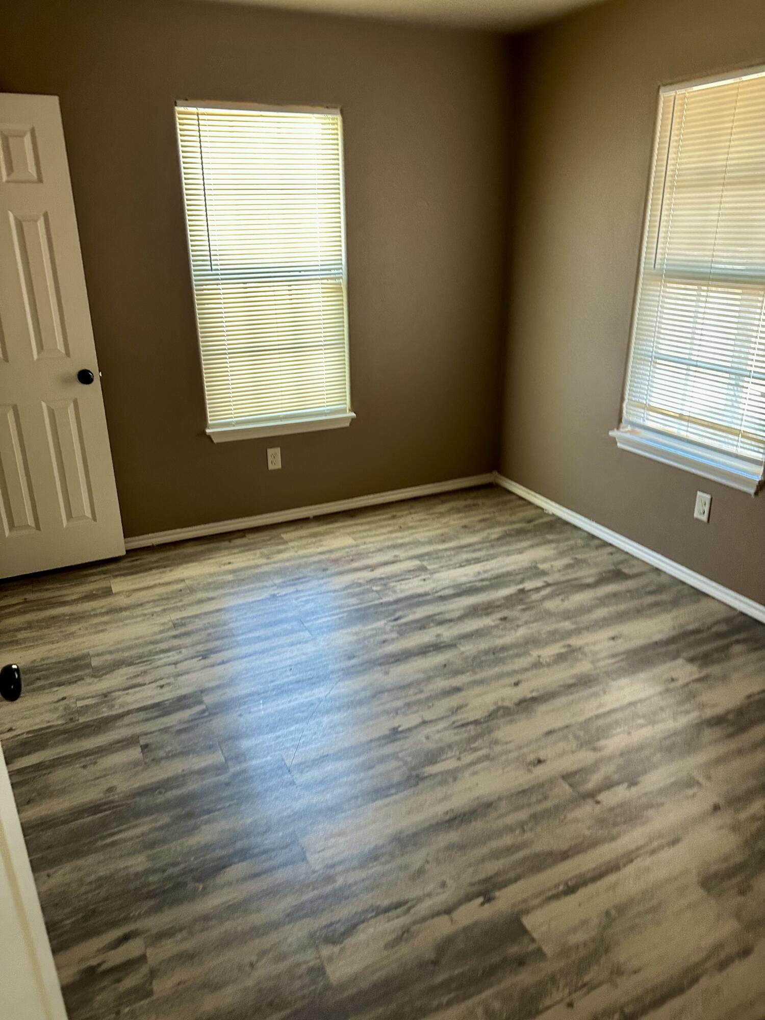 118 81st Street, Unit 1 Lubbock, TX 79404 - Photo 3 of 10 an empty room with wooden floor and windows