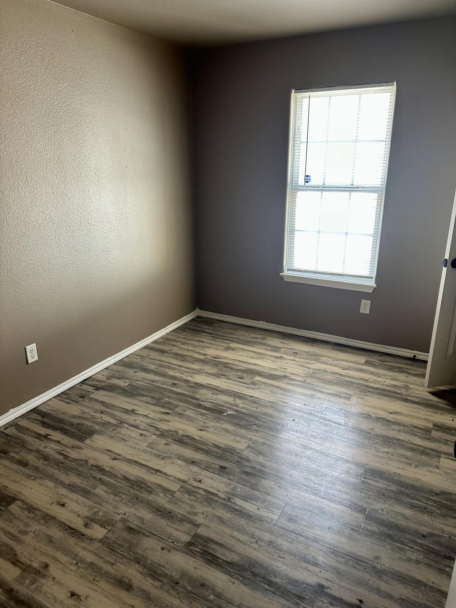 118 81st Street, Unit 1 Lubbock, TX 79404 - Photo 4 of 10 an empty room with wooden floor and windows