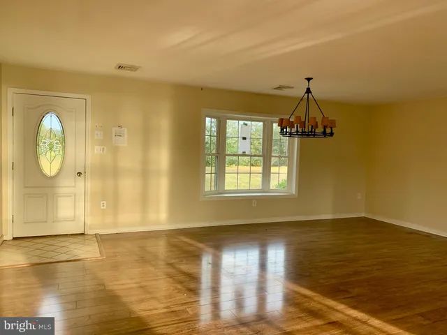 a view of empty room with window and wooden floor