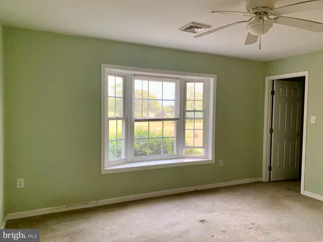 an empty room with a window and ceiling fan