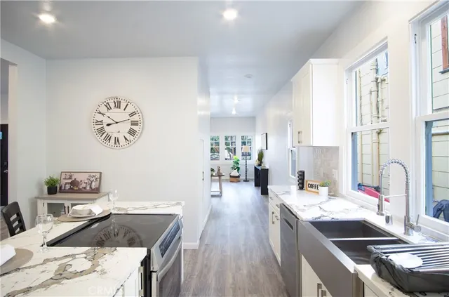 a kitchen with a refrigerator a stove a sink and a dining table with wooden floor