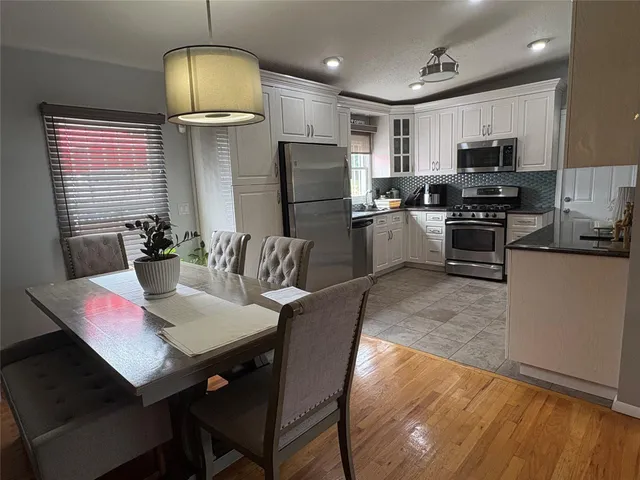 a kitchen with sink microwave refrigerator dining table and chairs