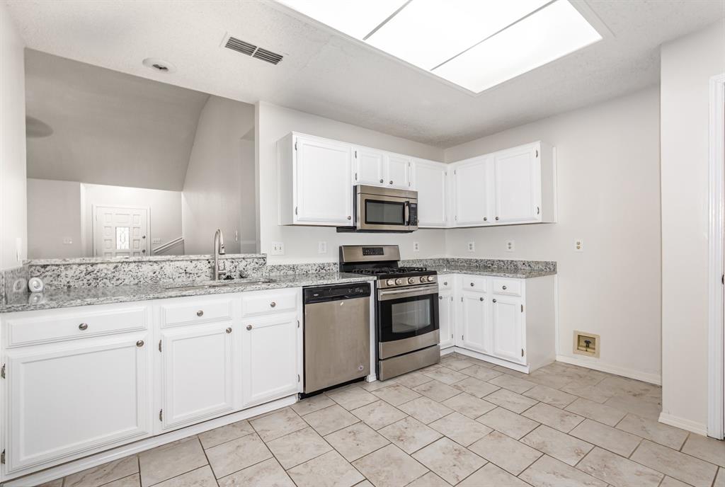 1046 Colony Street Flower Mound, TX 75028 - Photo 7 of 19 a kitchen with granite countertop white cabinets and stainless steel appliances