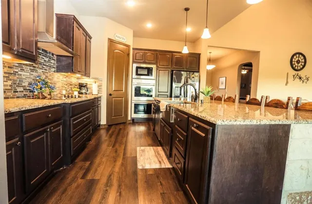 a kitchen with stainless steel appliances granite countertop a stove a sink dishwasher and a refrigerator