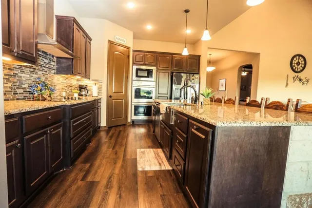 a kitchen with stainless steel appliances granite countertop a stove a sink dishwasher and a refrigerator