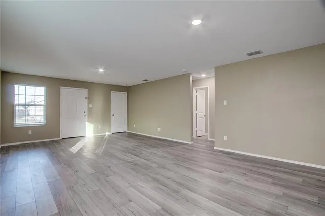 a view of an empty room with wooden floor and windows