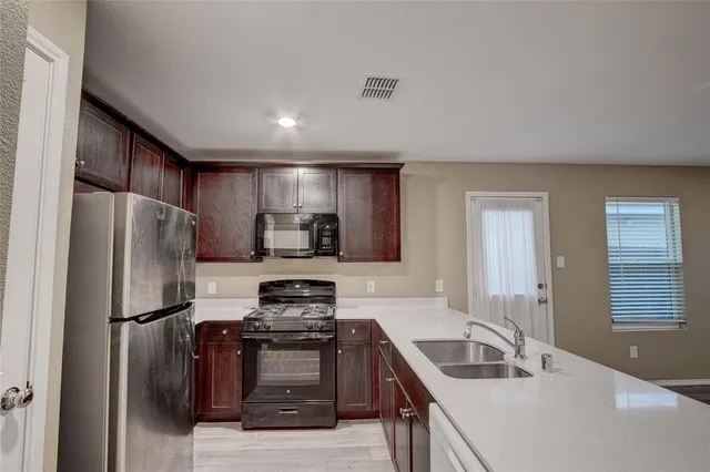 a kitchen with a refrigerator sink and wooden cabinets
