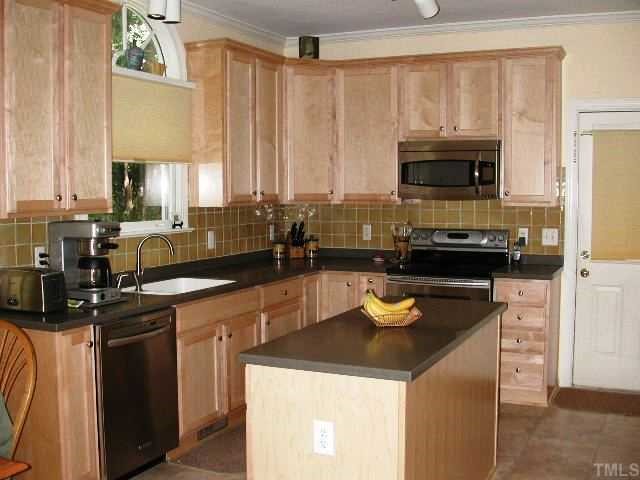 4412 Queenstown Court Raleigh, NC 27612 - Photo 3 of 11 a kitchen with stainless steel appliances a stove a sink and a microwave