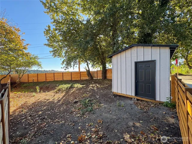 a view of a backyard with large trees and wooden fence