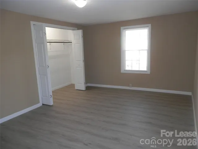 an empty room with wooden floor cabinet and windows