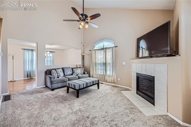 12510 Motley Road Peyton, CO 80831 - Photo 5 of 36 Carpeted living room featuring high vaulted ceiling, a tiled fireplace, and ceiling fan