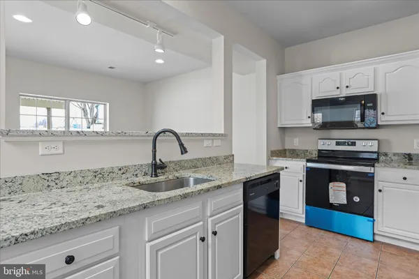 a kitchen with kitchen island granite countertop a sink stainless steel appliances and white cabinets