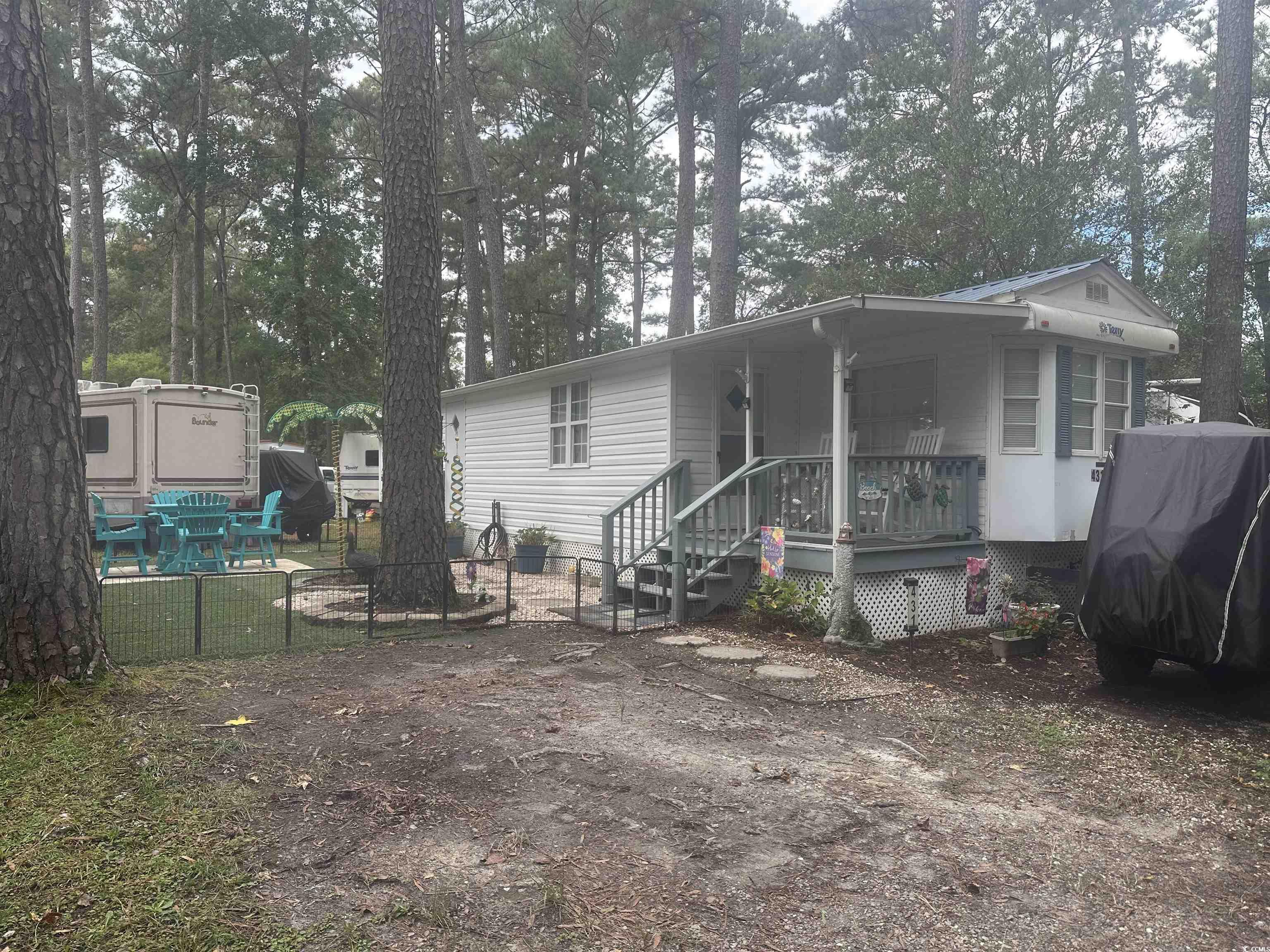 View of front facade featuring view of wooded area and a porch
