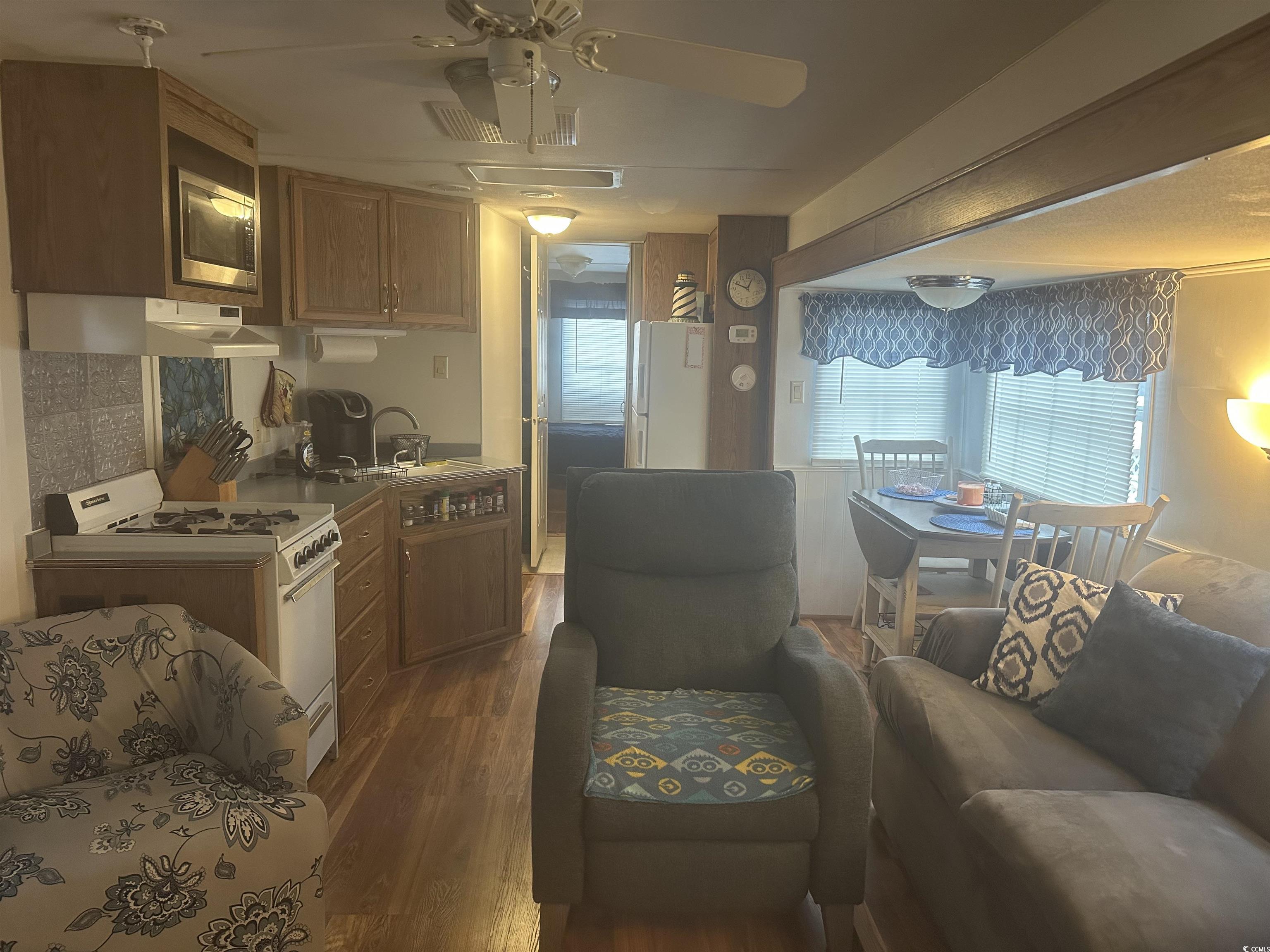 613-431 5th Avenue South Myrtle Beach, SC 29577 - Photo 36 of 36 Kitchen featuring brown cabinets, white appliances, open floor plan, dark wood-type flooring, and a ceiling fan