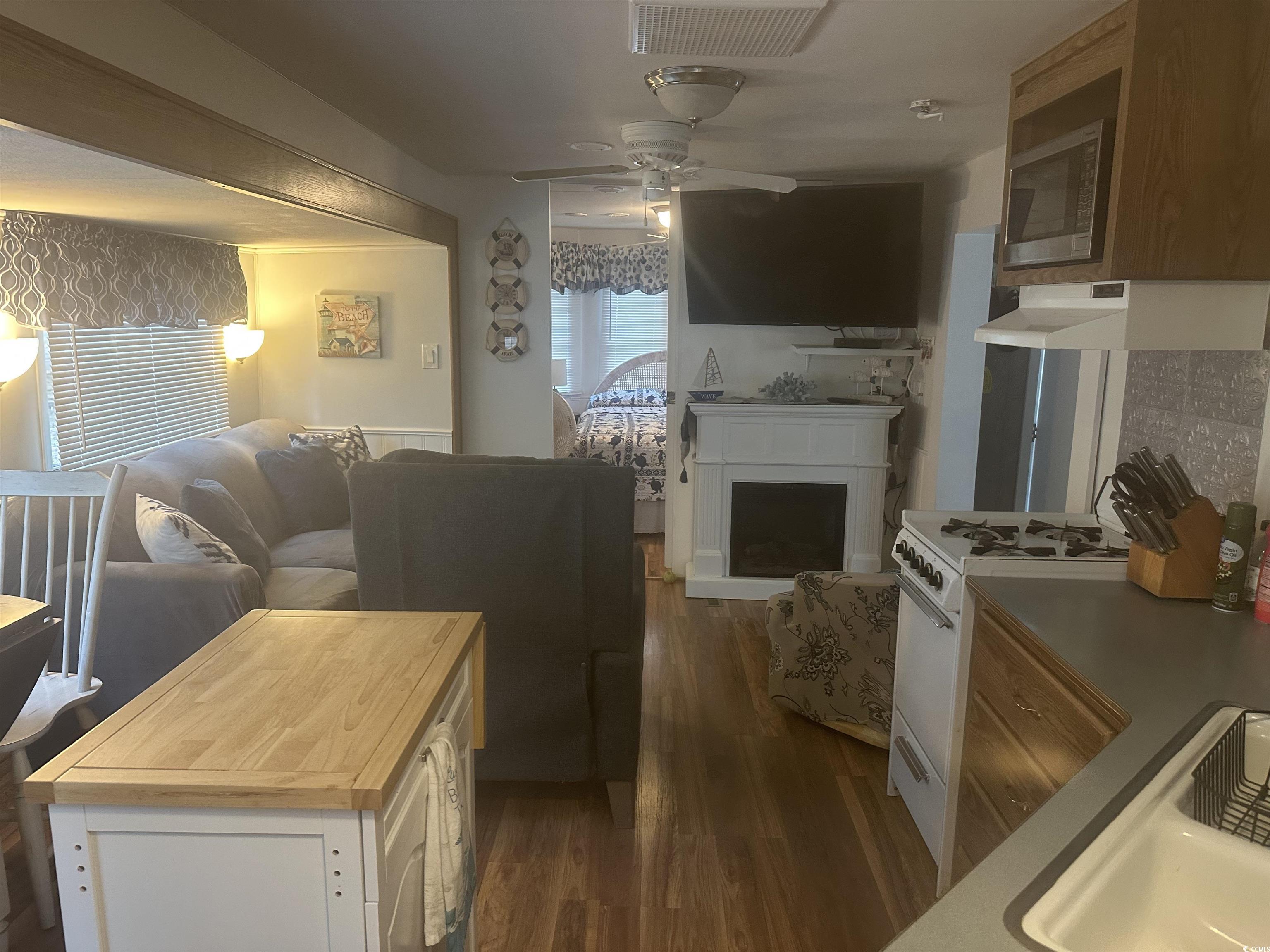 613-431 5th Avenue South Myrtle Beach, SC 29577 - Photo 9 of 36 Living room featuring dark wood finished floors, ceiling fan, and a fireplace