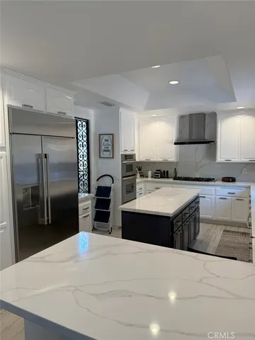 a kitchen with stainless steel appliances kitchen island granite countertop a refrigerator and a stove top oven